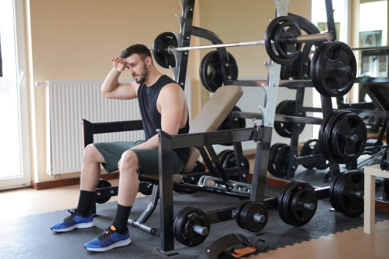 An adjustable weight bench beside a loaded barbell rack at home