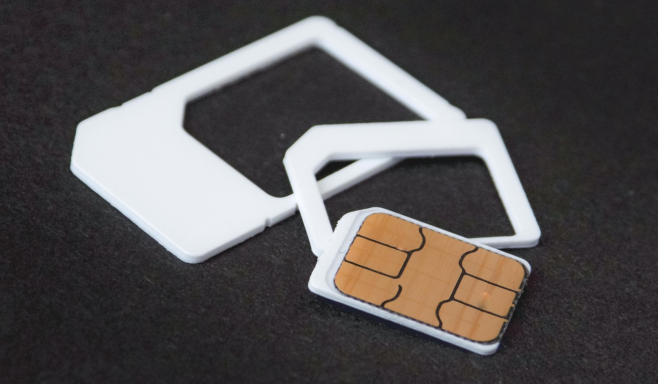 A nano SIM card resting on white SIM card adapters