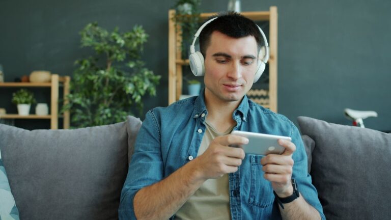 The Data Allowances That Outlast a Month of Streaming Man on a sofa wearing headphones, watching a video on a phone held in landscape