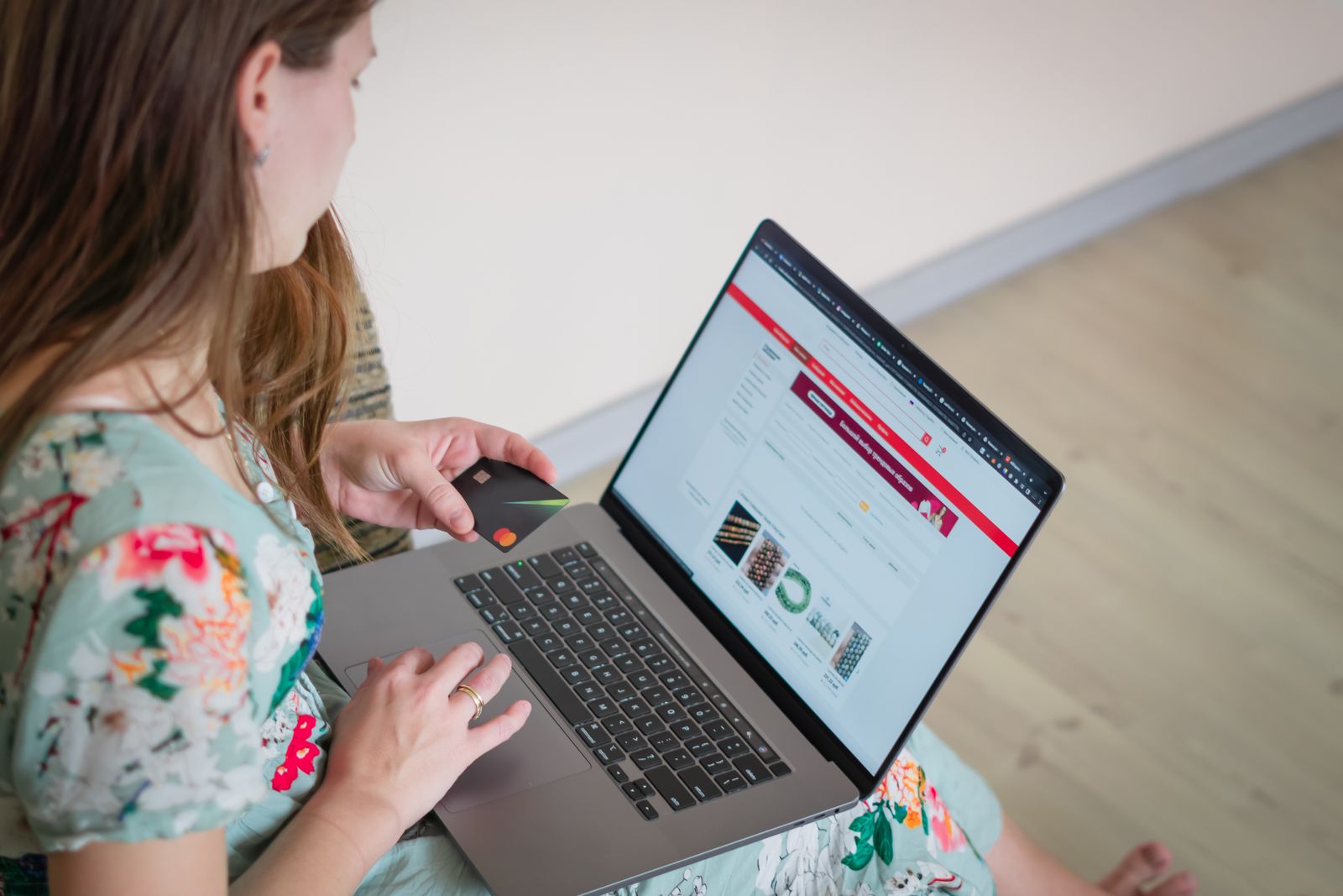 Woman shopping online on a laptop with a card in hand