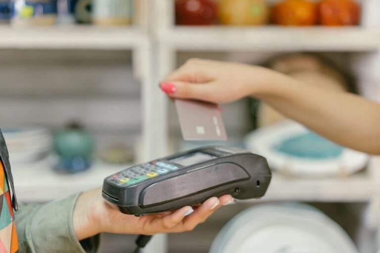 The Credit Cards That Earn More at Grocery and Electronics Stores Shop assistant holding a card machine as a plain card is tapped