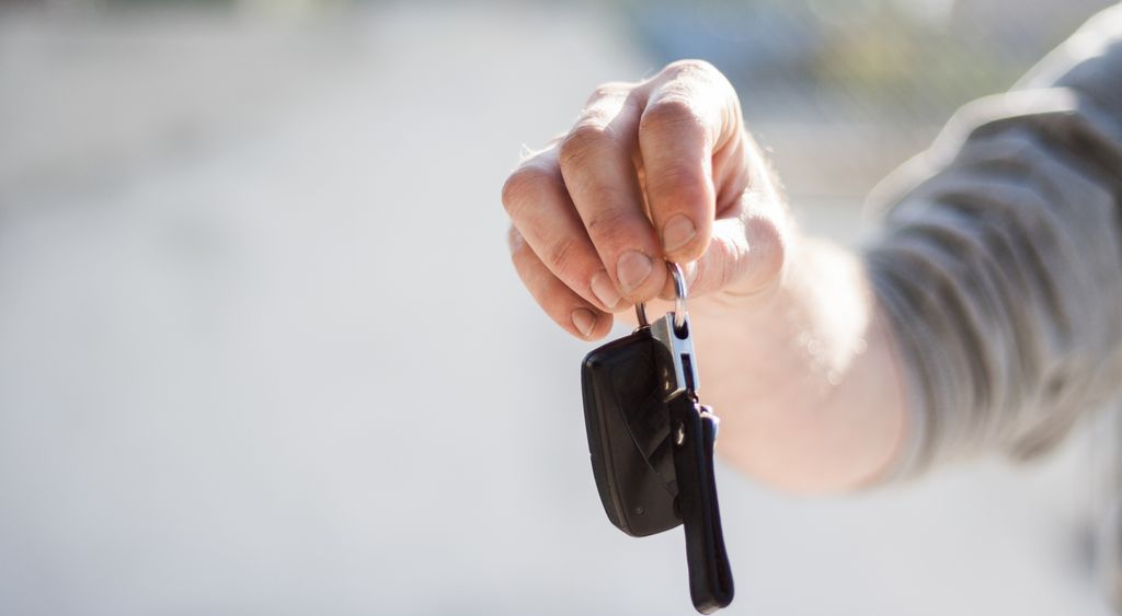 Hand holding out a car key for a rental pickup