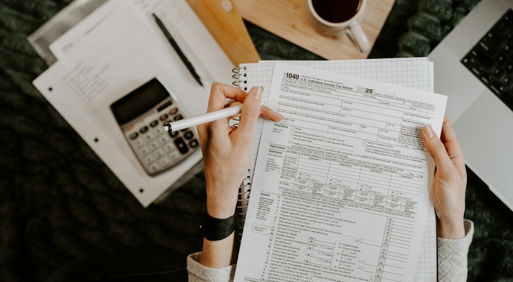 Hands working through household bills with a calculator