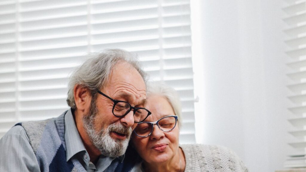Dental, Vision and Hearing Benefits That Come With Membership Older couple sitting together by a window, both wearing glasses
