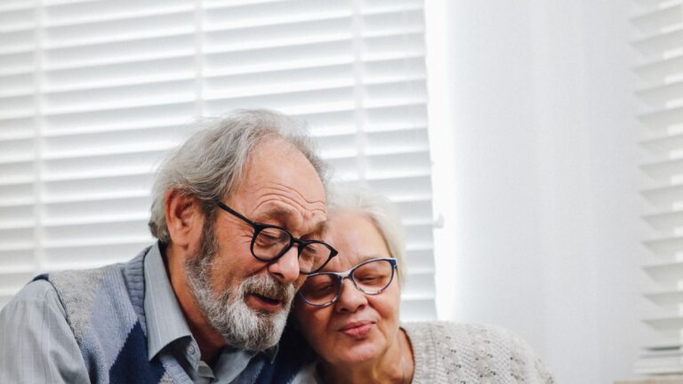 Dental, Vision and Hearing Benefits That Come With Membership Older couple sitting together by a window, both wearing glasses