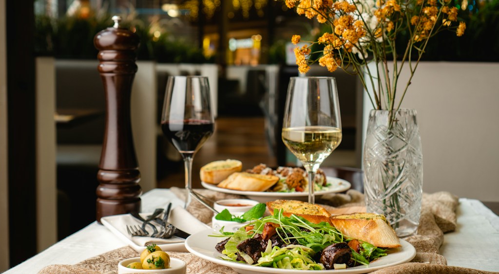 Plated meal and a glass of wine on a laid restaurant table