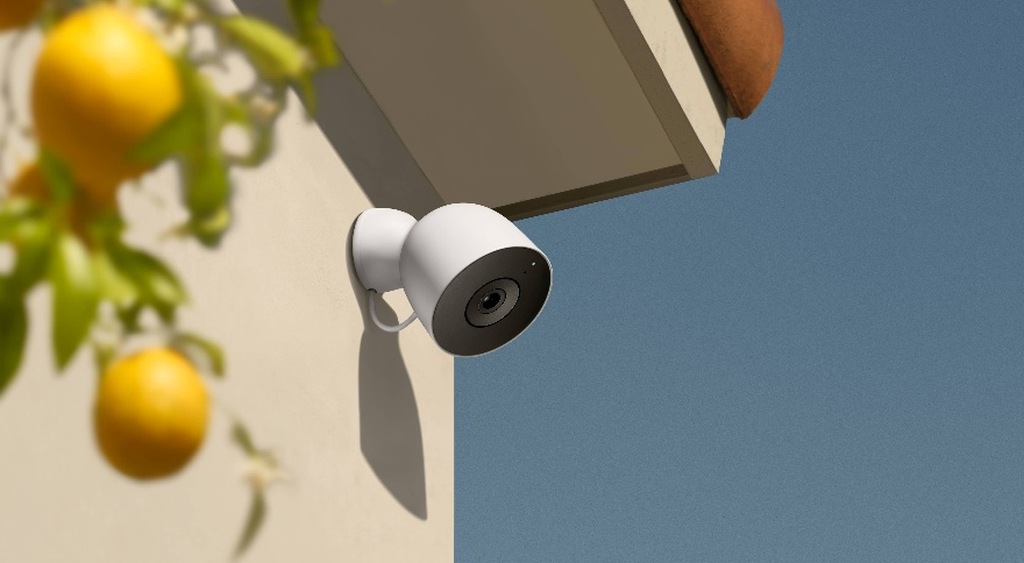 Outdoor security camera fixed beneath a roof overhang beside a lemon tree