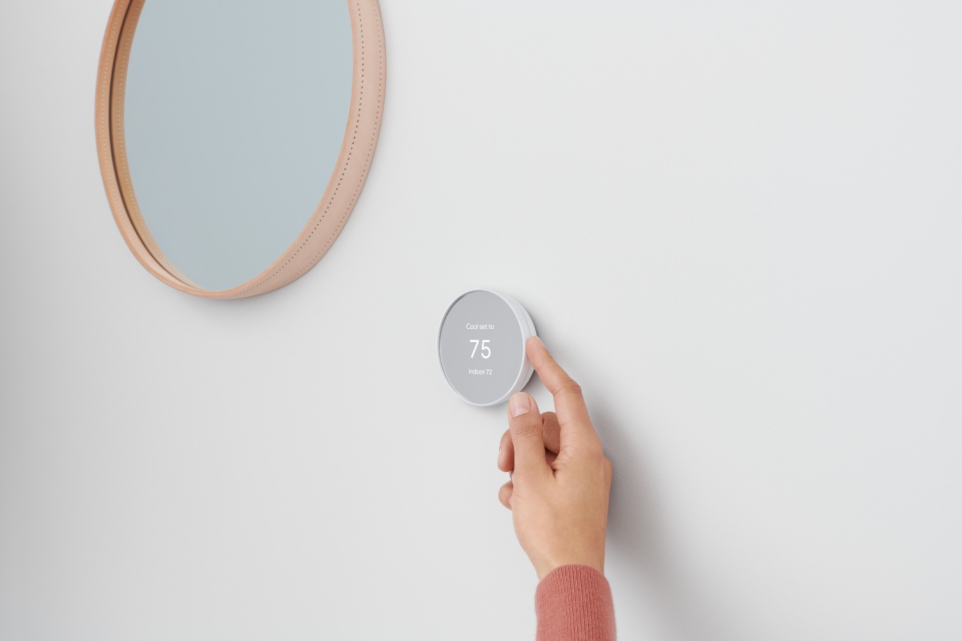 Hand adjusting a smart thermostat mounted on a wall