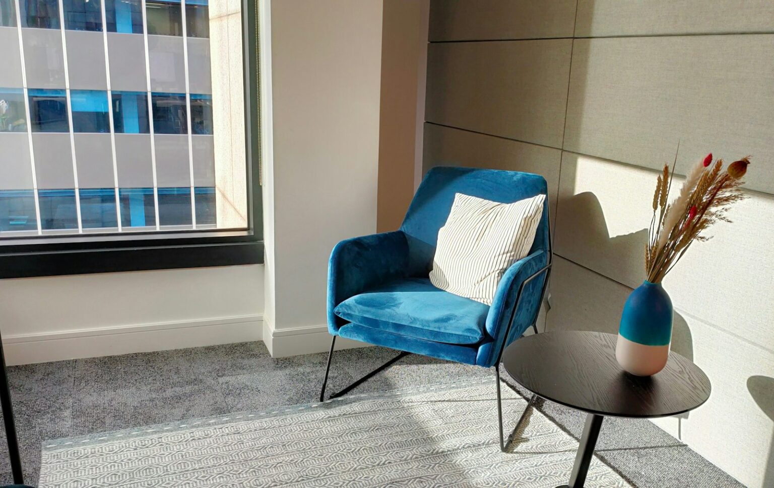 Armchairs That Fill a Corner Without Crowding the Room A blue velvet armchair in the corner of a room beside a window