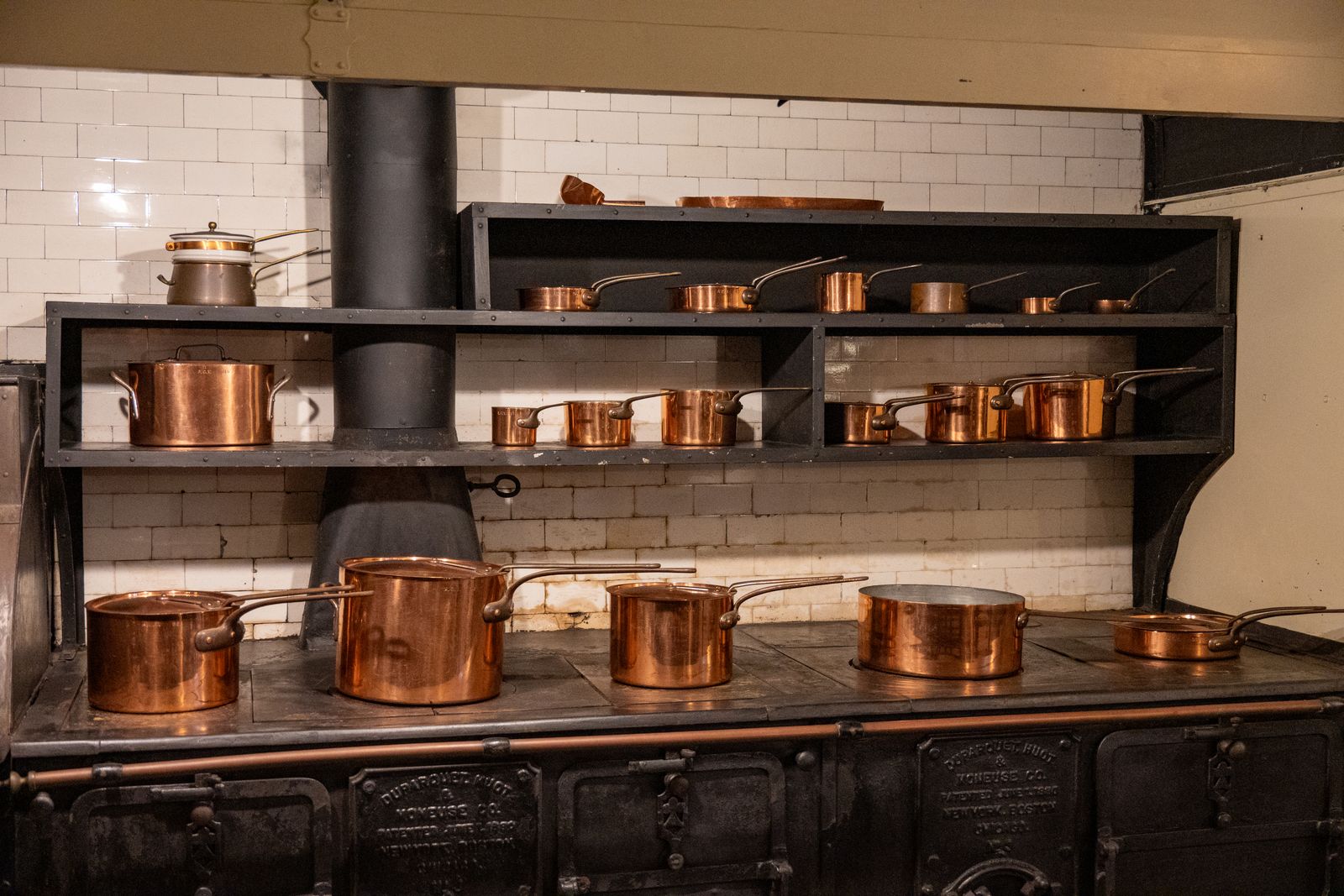 A set of copper pans on a rack above a range