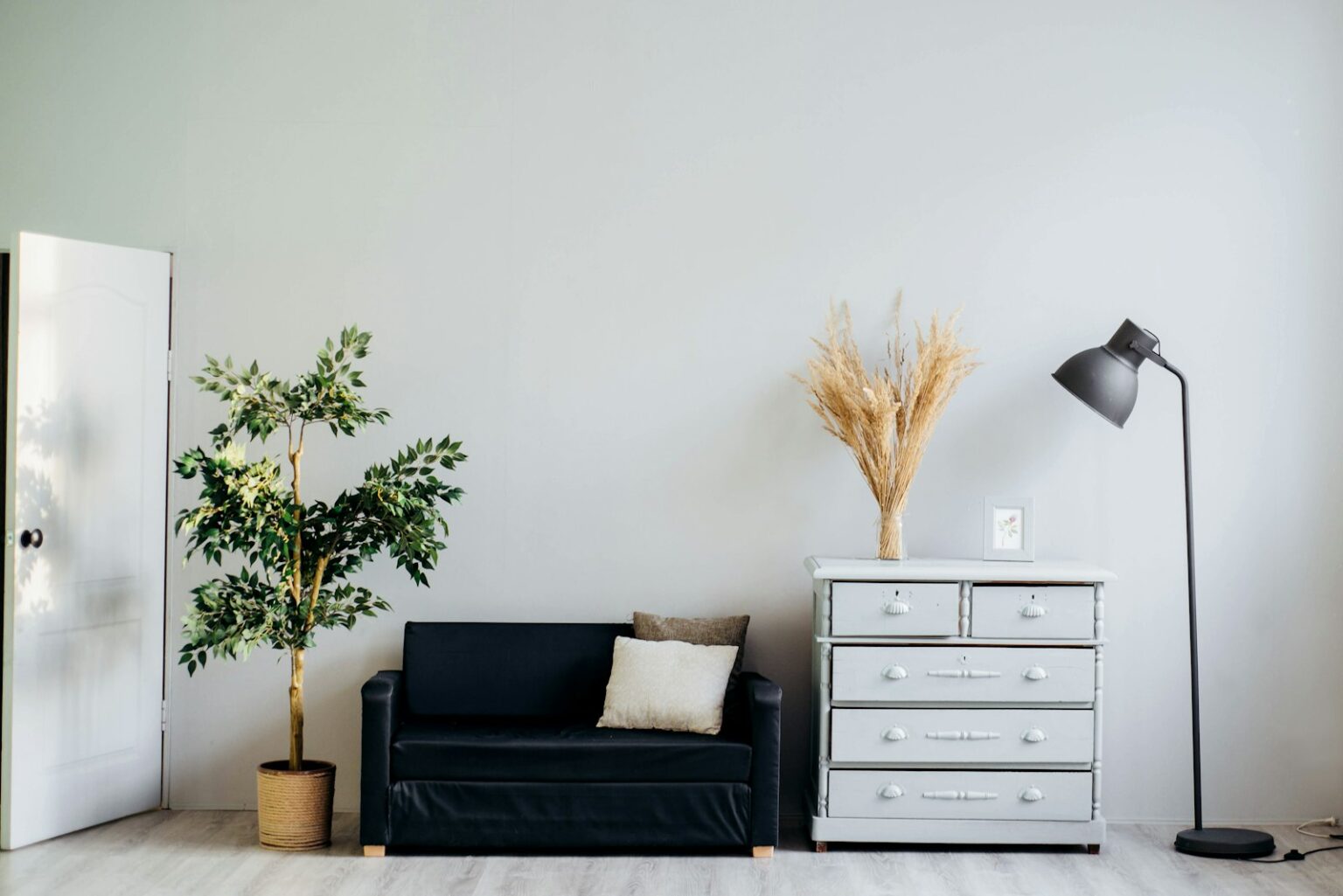 Best Lamps to Layer Light Across a Living Room A floor lamp standing beside a sofa in a bright living room