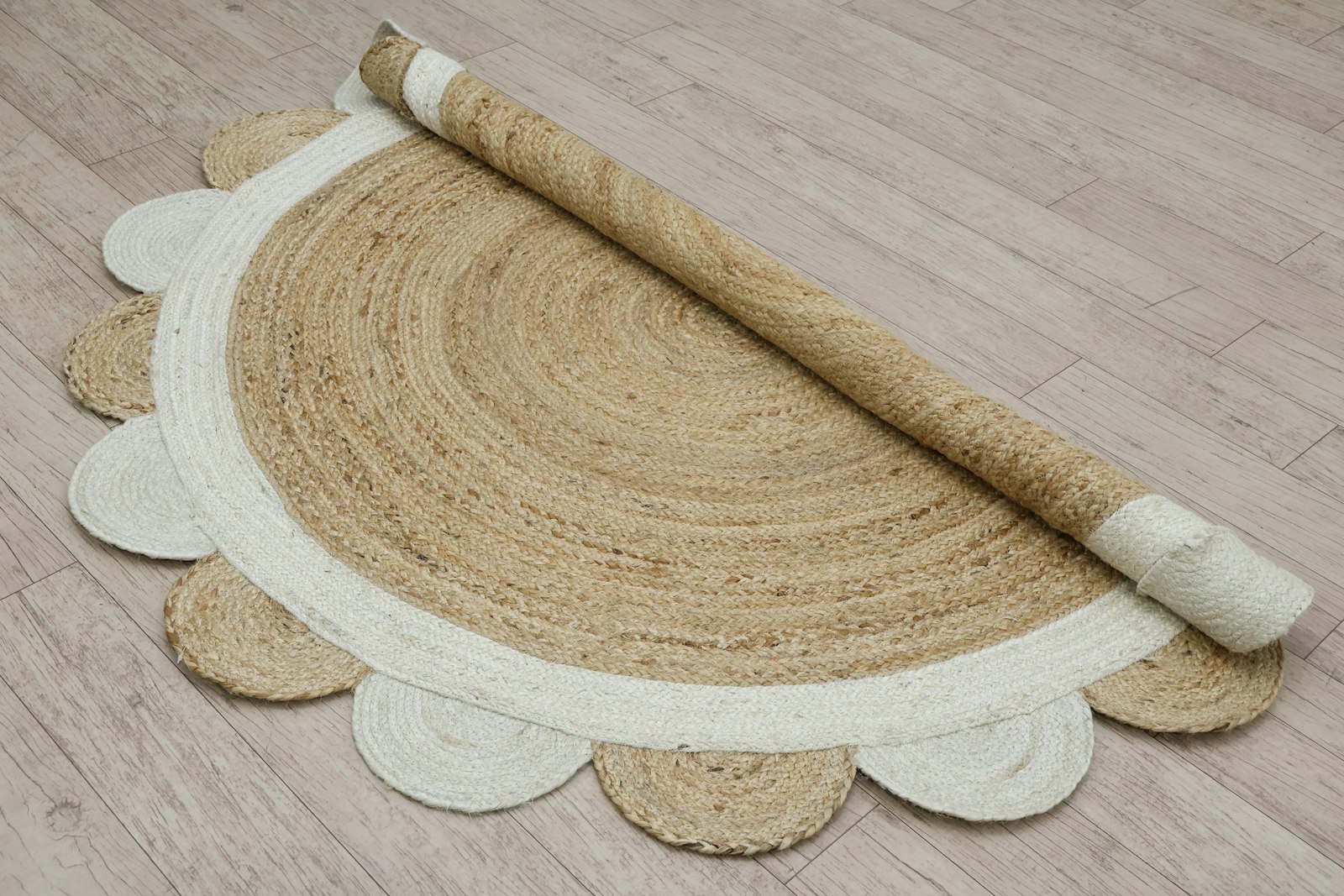 A round jute rug partly rolled back on a wooden floor