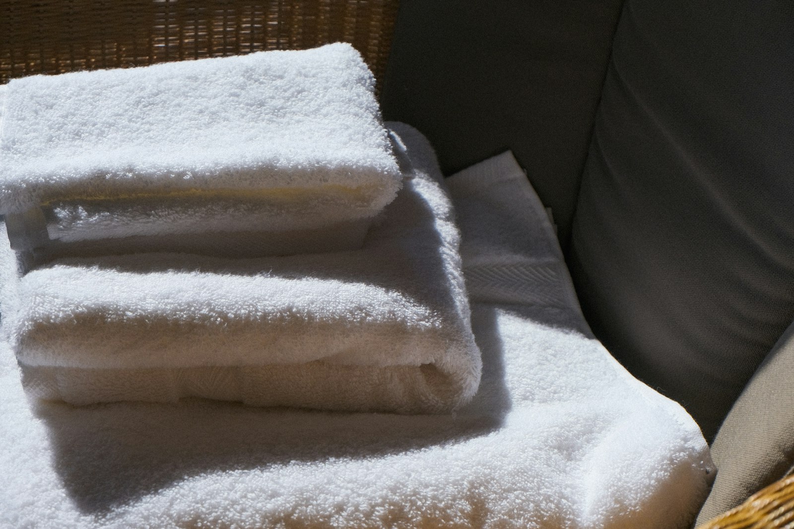 Folded white bath towels with a grey towel underneath