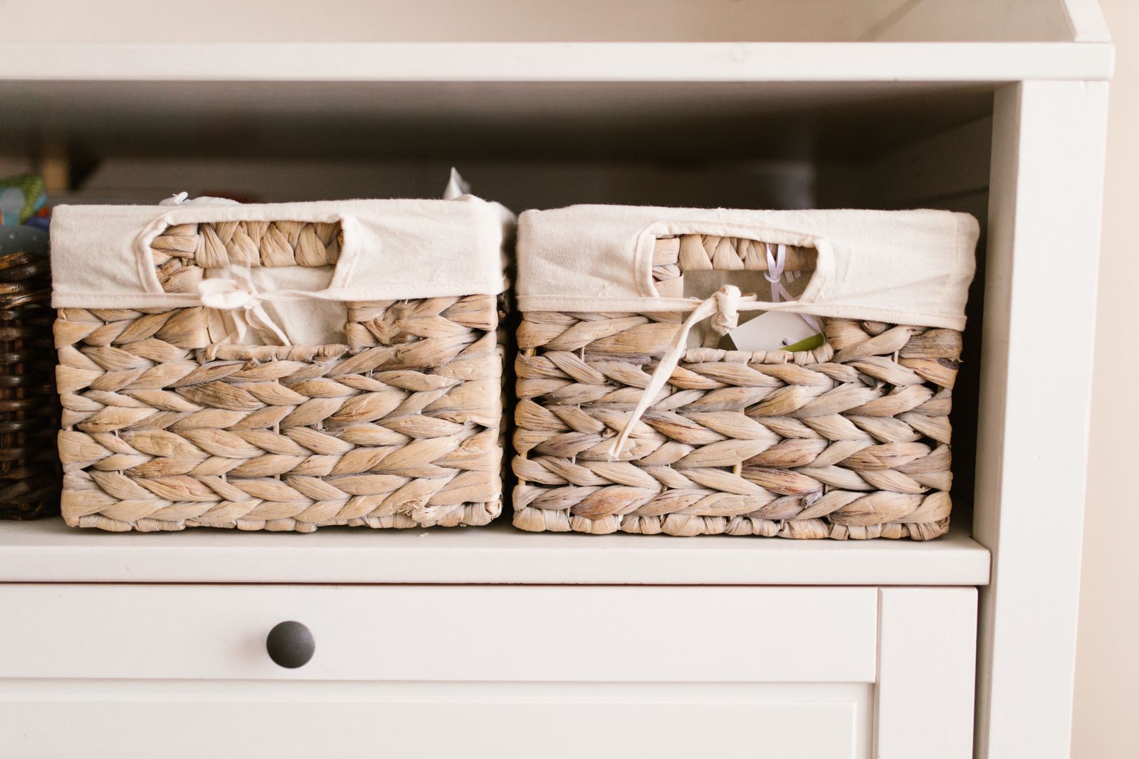 Two woven storage baskets in a white sideboard