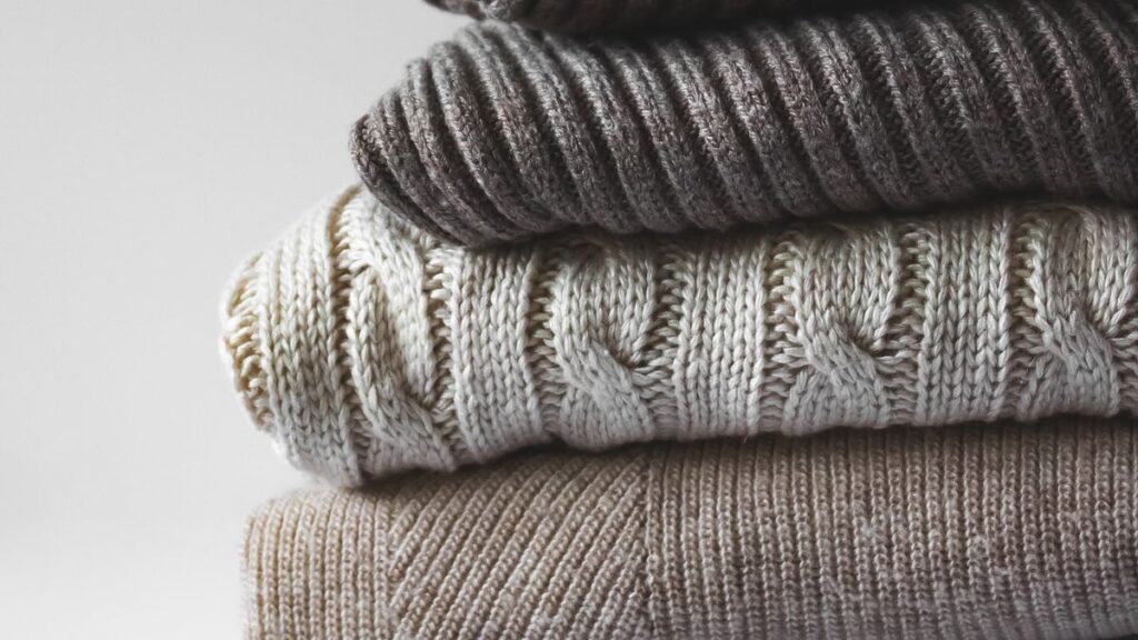 Wool Sweaters and Cardigans to Wear All Winter Without Fuss A stack of folded ribbed and cable knit wool sweaters