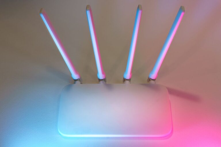 White wireless router with four glowing antennas on a desk