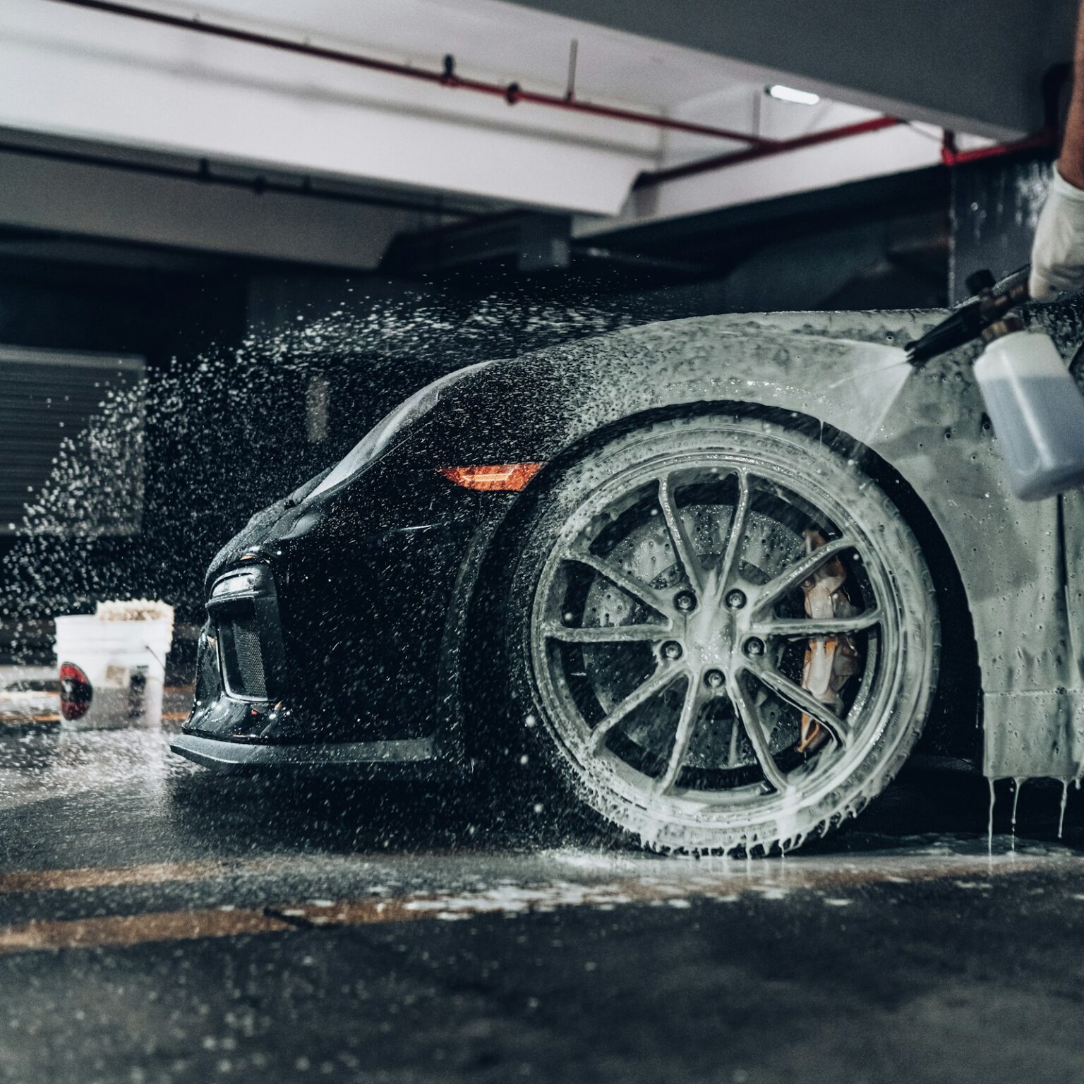 Shampoings et Soins Céramique Auto pour une Carrosserie Protégée Car being rinsed down with foam and spray in a wash bay