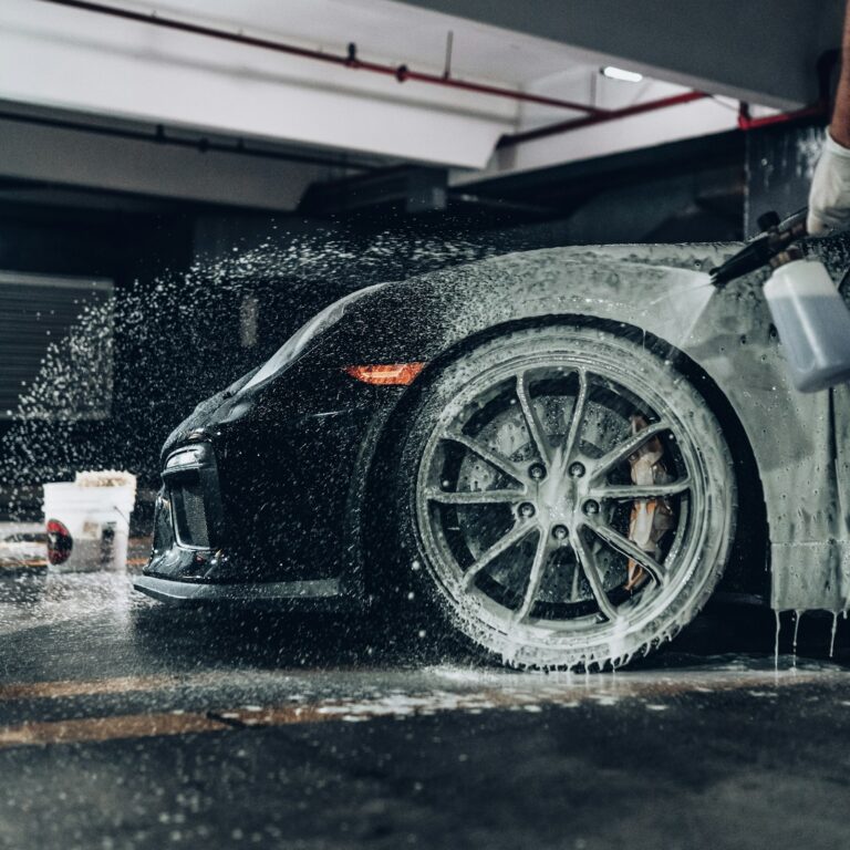 Shampoings et Soins Céramique Auto pour une Carrosserie Protégée Car being rinsed down with foam and spray in a wash bay