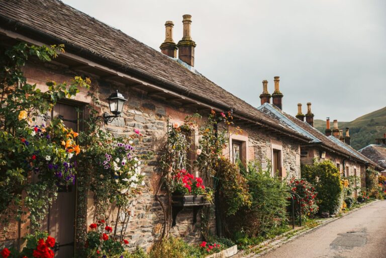 Row of neighbouring stone cottages with flowers along a quiet lane