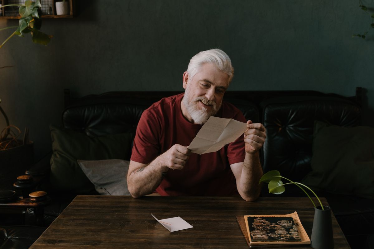 Man reading a letter at a table at home