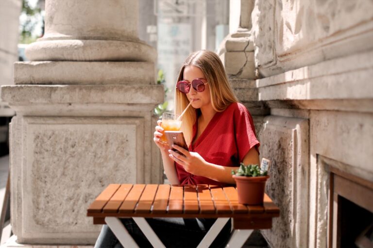Un abonnement presse pour les rubriques voyage, style et vin Lectrice consultant son téléphone à une terrasse ensoleillée