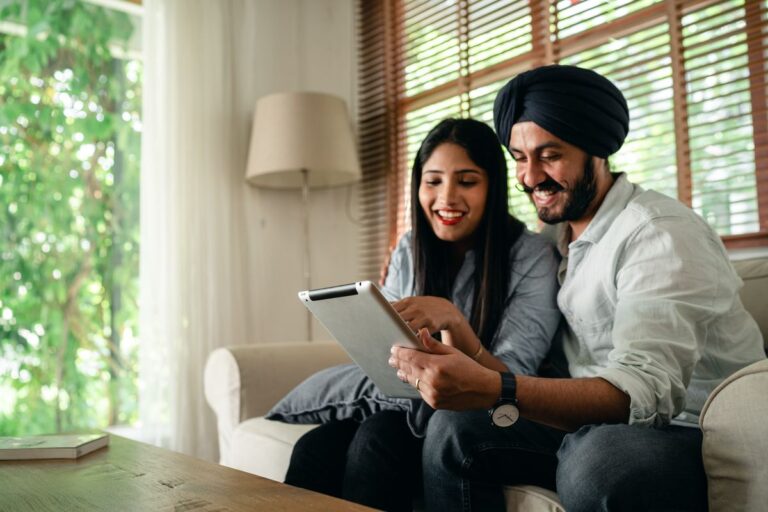 Couple sharing one tablet on a sofa at home