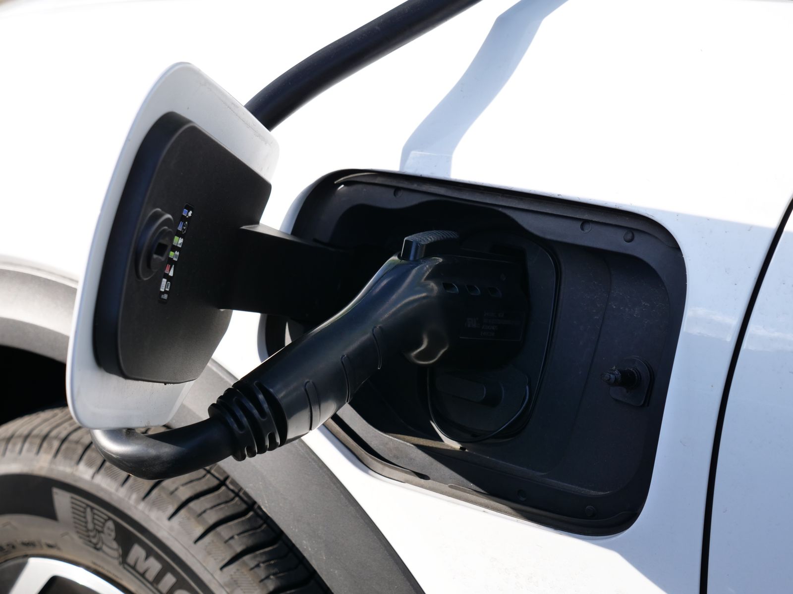Charging plug seated in the charge port of a white car