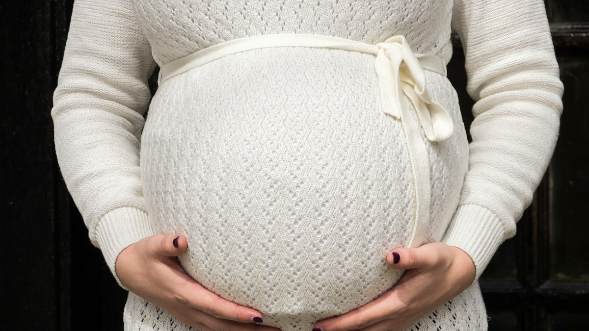 Femme enceinte en robe pull en maille ajourée