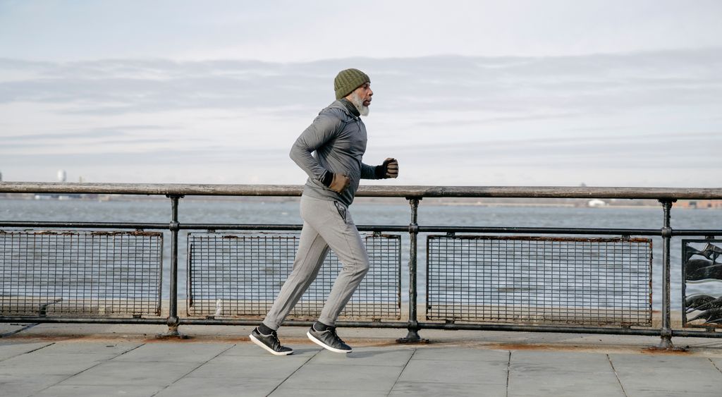 A runner in cold-weather layers along a waterfront