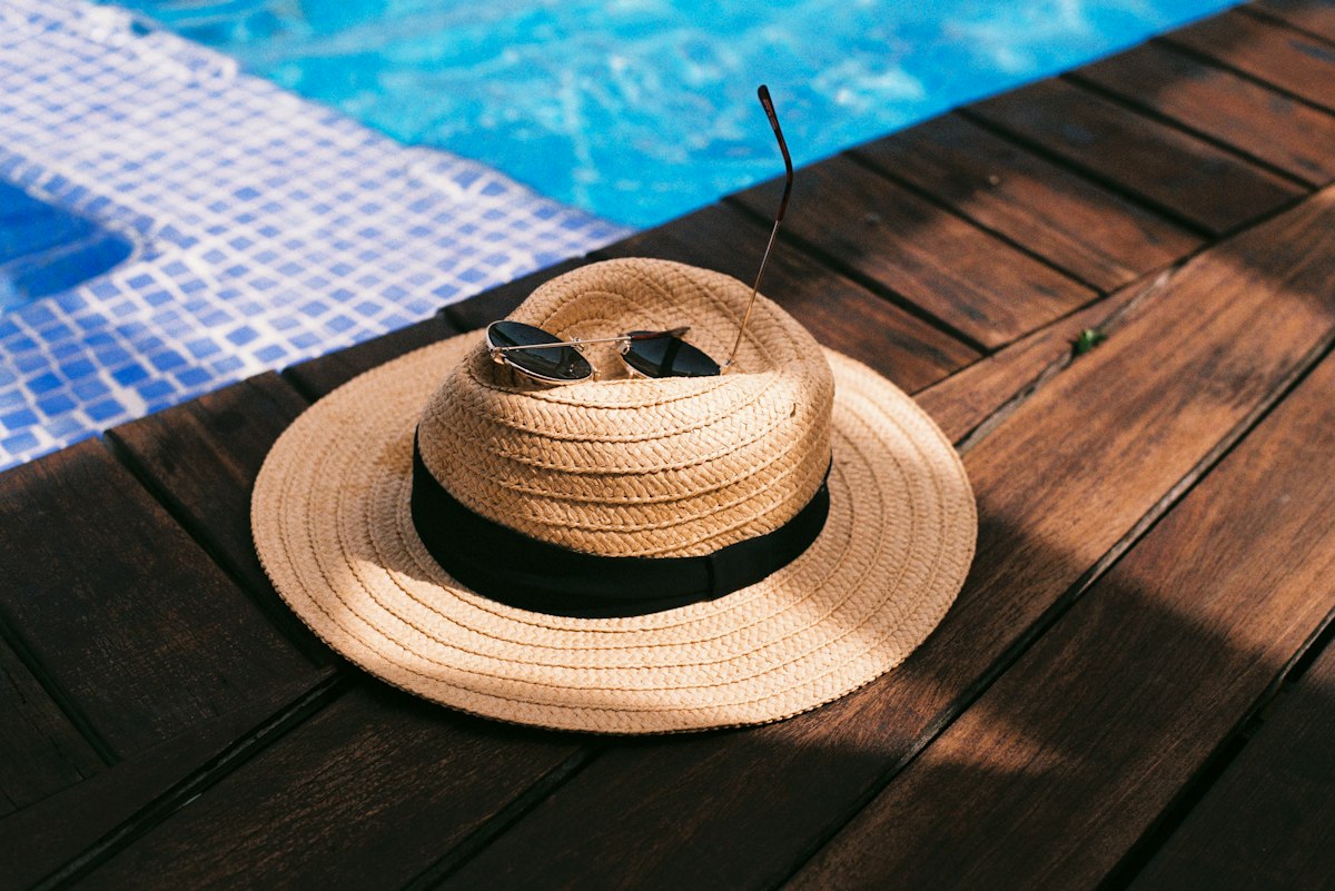 Chapeau de paille et lunettes de soleil au bord d'une piscine