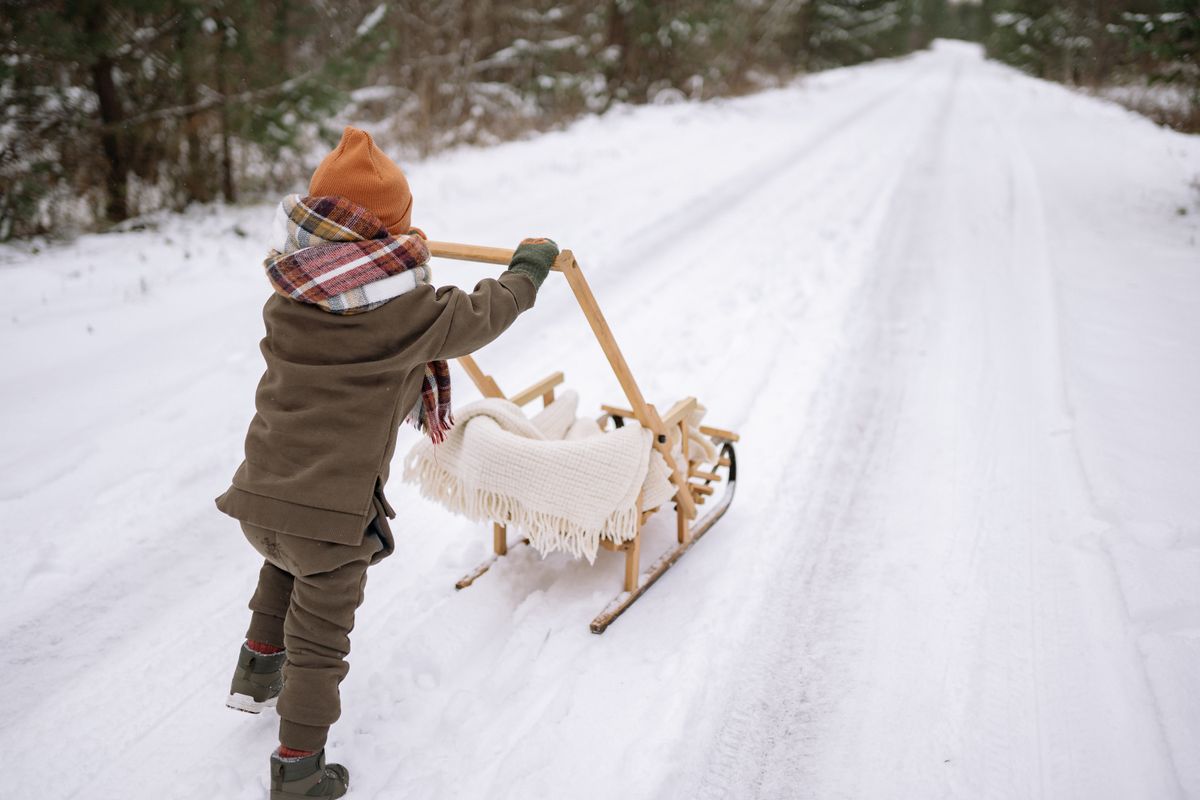Enfant en manteau d'hiver avec une luge