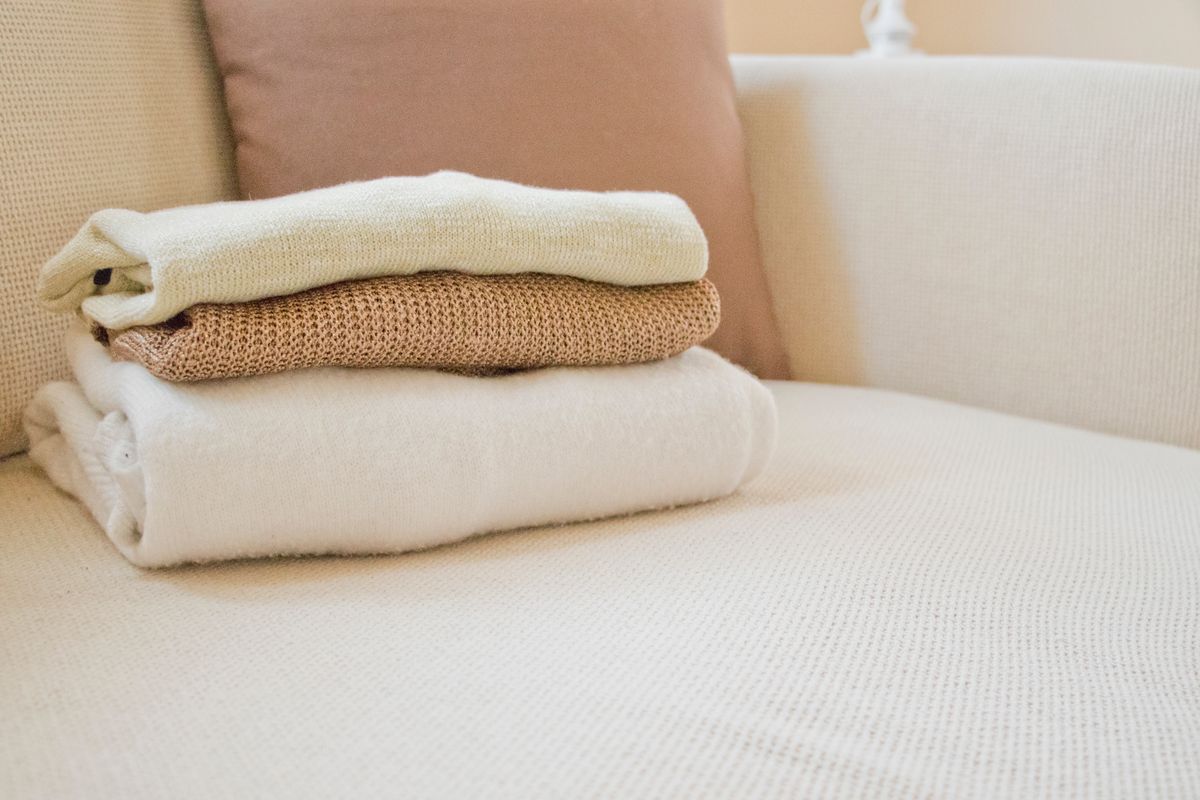 A stack of folded knitwear on a sofa