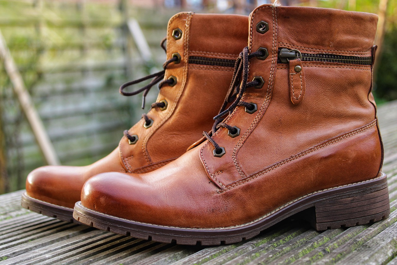 Pair of tan leather lace-up boots on a wooden deck