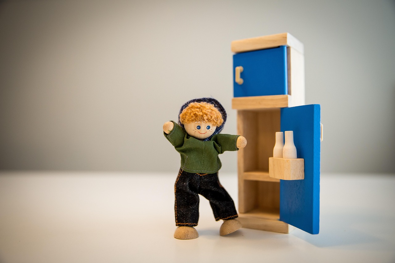 Wooden toy fridge with a wooden doll
